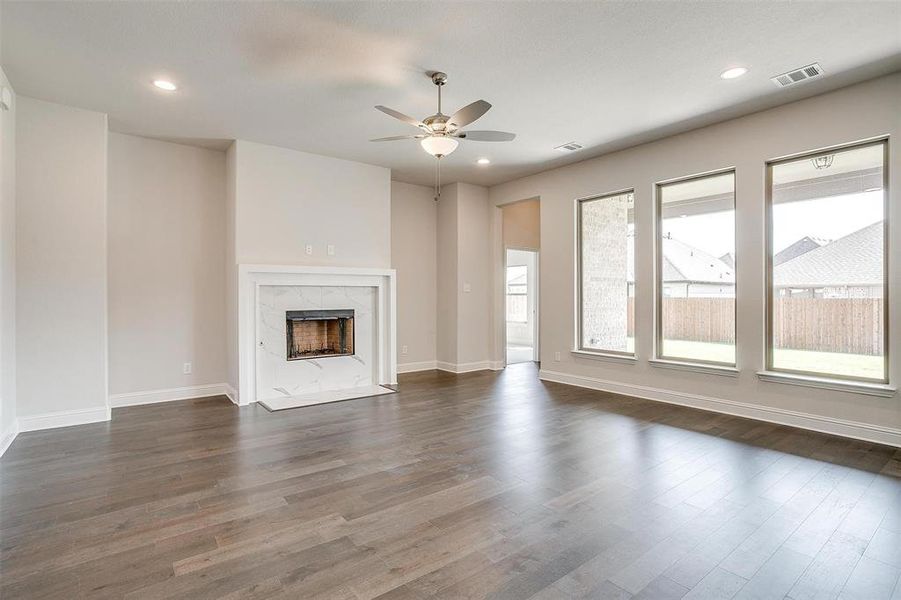 Unfurnished living room with ceiling fan, a premium fireplace, and dark wood-type flooring