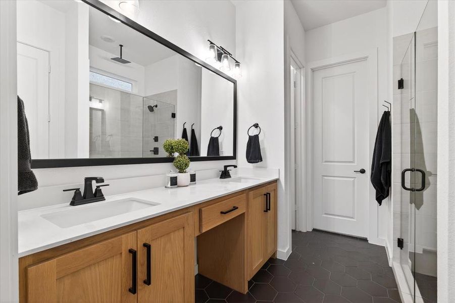 Bathroom with a stall shower, double vanity, and dark tile patterned flooring Bathroom with a stall shower, double vanity, and dark tile patterned flooring