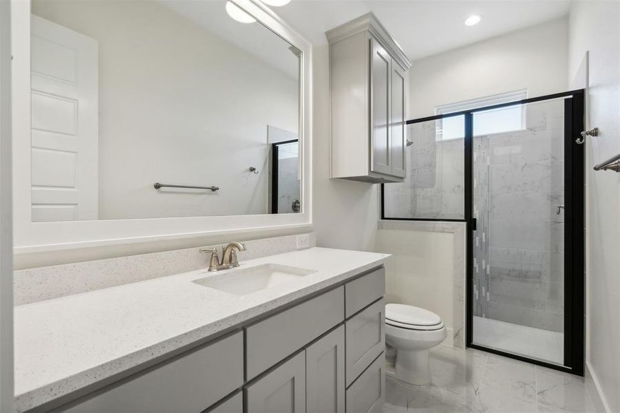 Bathroom with vanity, a shower with shower door, and toilet