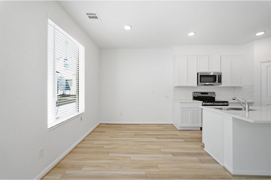 Kitchen featuring white cabinetry, stainless steel appliances, light wood-style floors, backsplash, and recessed lighting Kitchen featuring white cabinetry, stainless steel appliances, light wood-style floors, backsplash, and recessed lighting