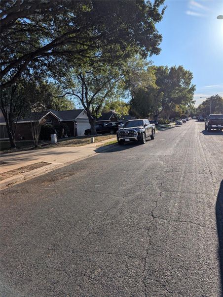 View of asphalt road featuring street lighting, sidewalks, and curbs