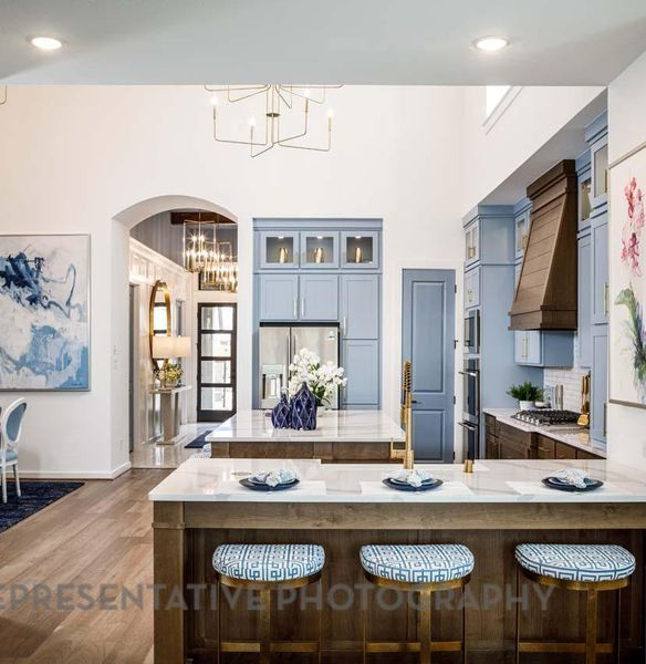 Kitchen with a chandelier, stainless steel appliances, a kitchen bar, dark wood-style floors, and glass insert cabinets Kitchen with a chandelier, stainless steel appliances, a kitchen bar, dark wood-style floors, and glass insert cabinets