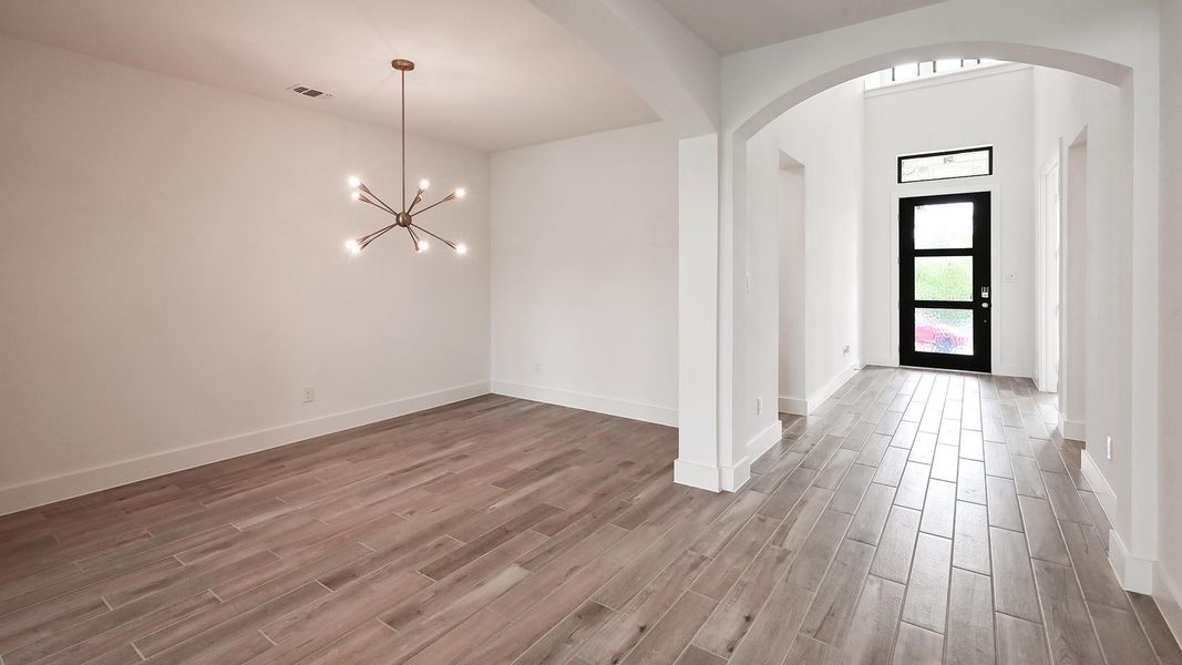 Foyer featuring arched walkways, a chandelier, wood finished floors, and baseboards Foyer featuring arched walkways, a chandelier, wood finished floors, and baseboards