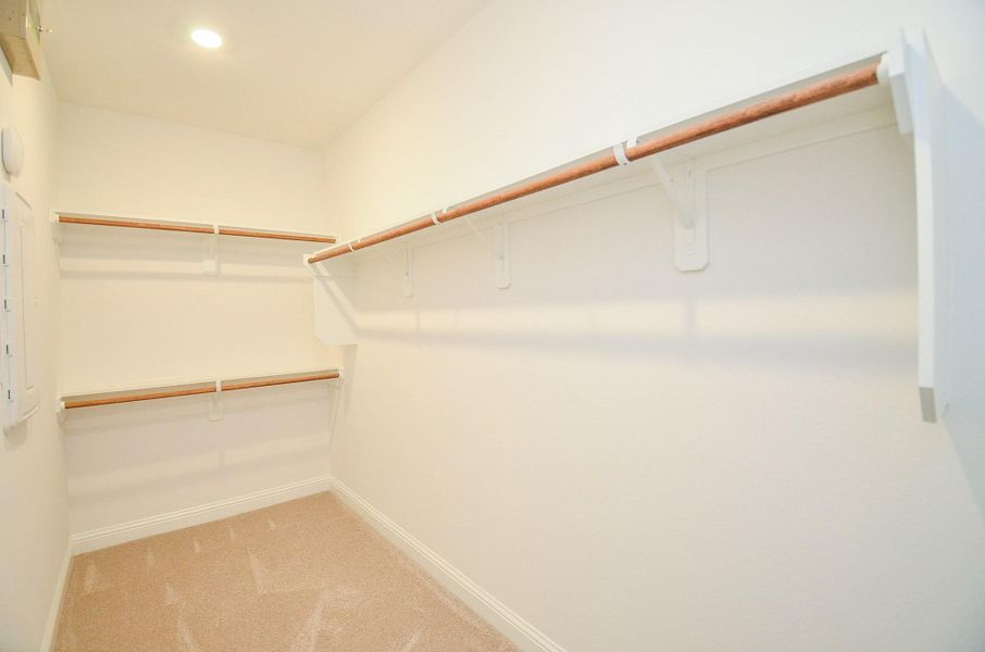 This is a spacious walk-in closet featuring carpeted floor and recessed lighting, ideal for ample storage and organization.