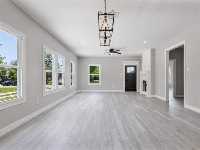 Unfurnished living room featuring light wood-style flooring, baseboards, recessed lighting, a ceiling fan, and a fireplace Unfurnished living room featuring light wood-style flooring, baseboards, recessed lighting, a ceiling fan, and a fireplace