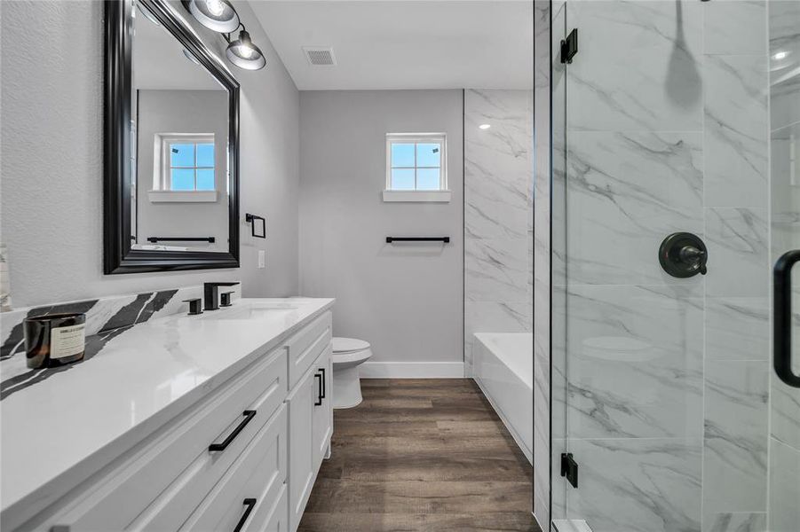 Full bathroom with hardwood / wood-style floors, vanity, toilet, and independent shower and bath