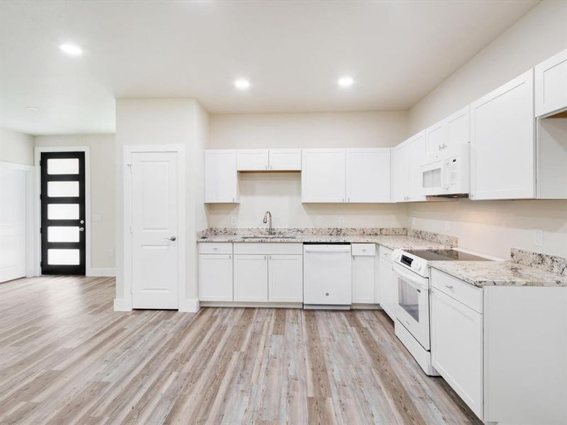 Modern kitchen featuring white cabinetry, light-colored countertops, and white appliances Modern kitchen featuring white cabinetry, light-colored countertops, and white appliances
