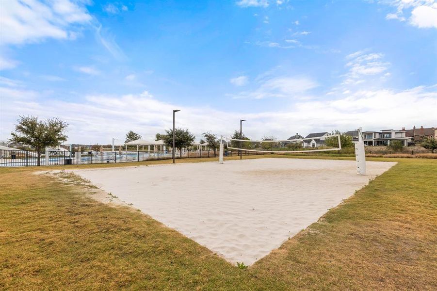 View of community with volleyball court, a yard, and fence