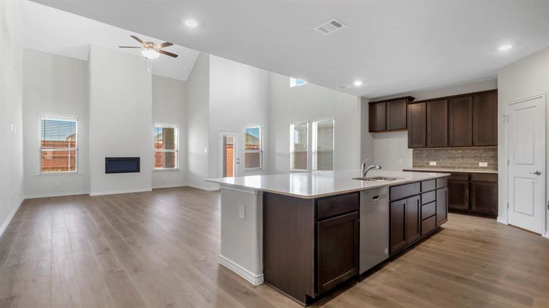 Open-concept living space featuring wood-finish flooring, a contemporary fireplace, and a ceiling fan