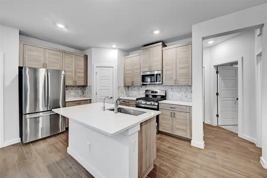 Kitchen with stainless steel appliances, light wood-style flooring, light countertops, tasteful backsplash, and recessed lighting Kitchen with stainless steel appliances, light wood-style flooring, light countertops, tasteful backsplash, and recessed lighting