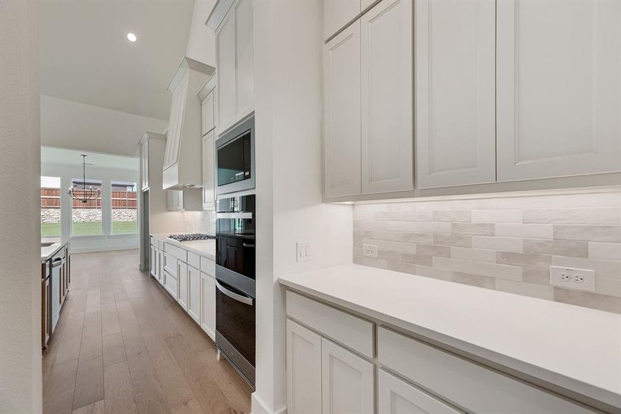 Kitchen with white cabinetry, decorative backsplash, recessed lighting, light wood finished floors, and appliances with stainless steel finishes