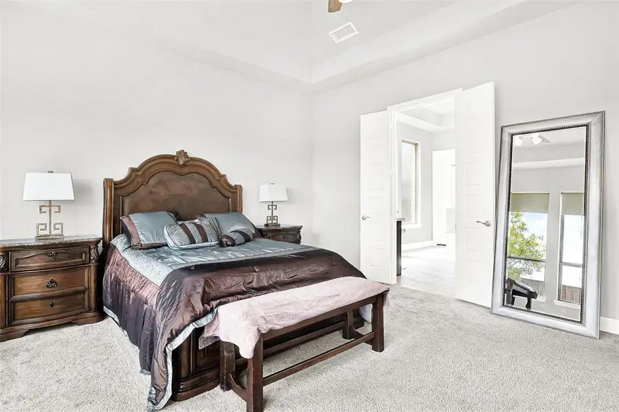 Bedroom featuring light carpet, ceiling fan, and a towering ceiling Bedroom featuring light carpet, ceiling fan, and a towering ceiling