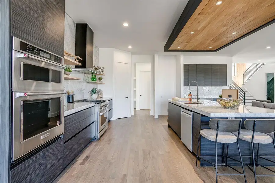 Kitchen with modern cabinets, light stone countertops, appliances with stainless steel finishes, recessed lighting, and a breakfast bar area Kitchen with modern cabinets, light stone countertops, appliances with stainless steel finishes, recessed lighting, and a breakfast bar area