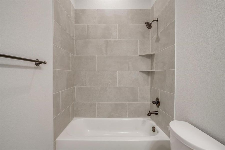 Bathroom with tiled shower / bath combo and toilet