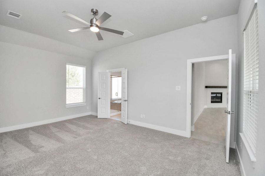 Come and unwind after a long day in this magnificent primary suite! This spacious room features plush carpet, warm paint, high ceilings and large windows with privacy blinds. Sample photo of completed home with similar floor plan. Actual colors and selections may vary.