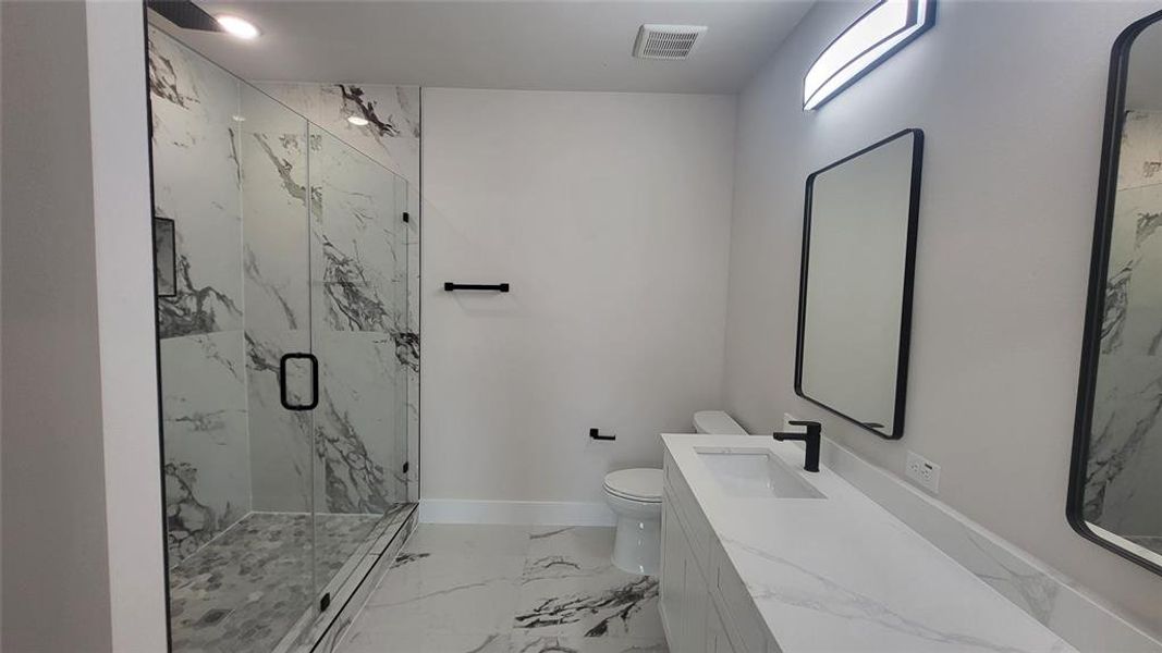 Full bath with a marble finish shower, toilet, visible vents, baseboards, and marble finish floor
