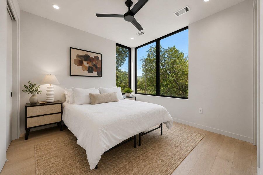 Floor-to-ceiling windows offer serene treetop views in this inviting sleeping area. Floor-to-ceiling windows offer serene treetop views in this inviting sleeping area.