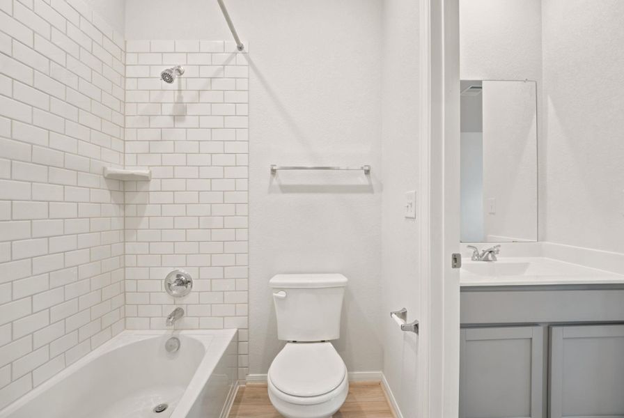Crisp subway tile accents the tub shower in this bathroom featuring a separate vanity nook.