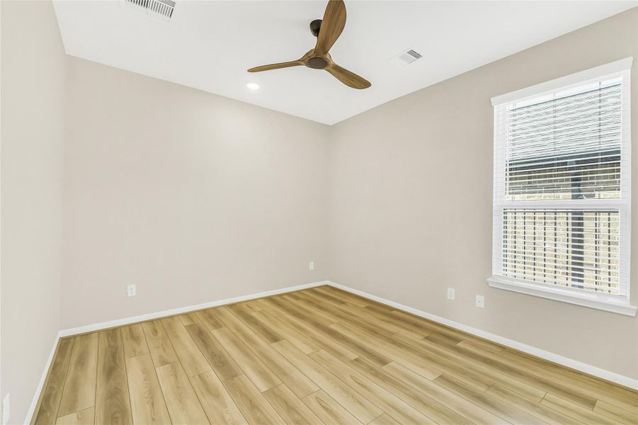Large windows and high-quality flooring make this third guest room feel open and inviting for visitors or family.