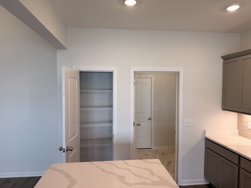 Pantry right off to the side of the Kitchen Island (left) and garage entry through the Laundry Room (right)! Home even has hardwired under cabinet LEDs!