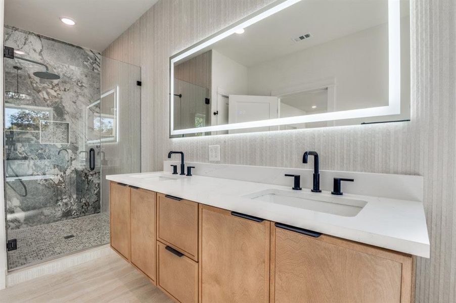 Full bath featuring double vanity and a marble finish shower