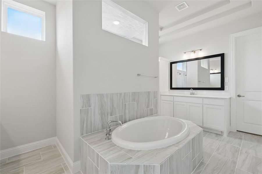 Full bath with a bath, vanity, and baseboards Full bath with a bath, vanity, and baseboards