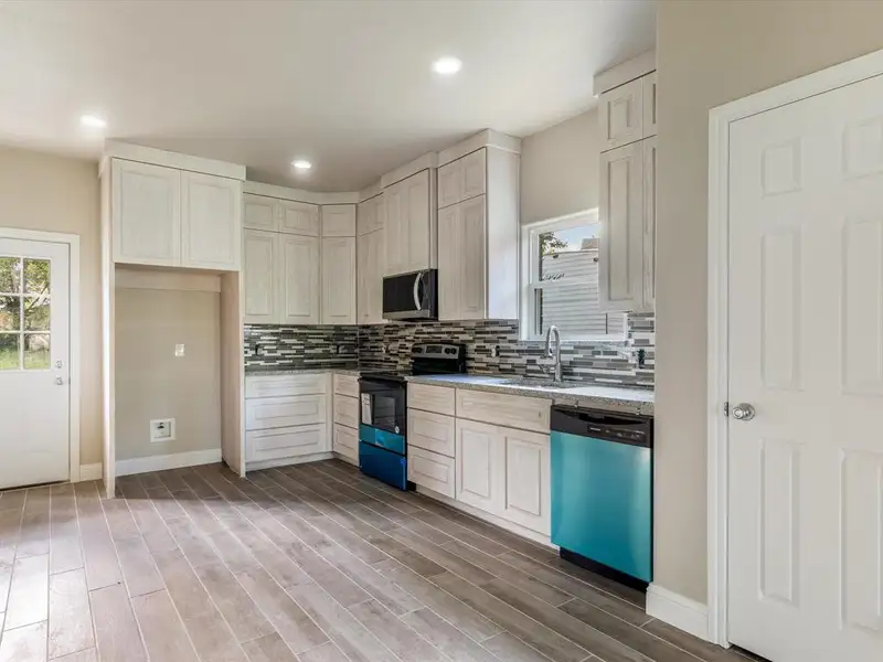 Kitchen with dishwashing machine, electric stove, stainless steel microwave, decorative backsplash, and light wood finished floors Kitchen with dishwashing machine, electric stove, stainless steel microwave, decorative backsplash, and light wood finished floors