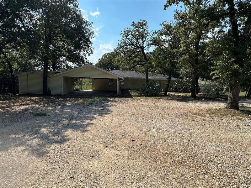 View of front of house with gravel driveway and an attached carport