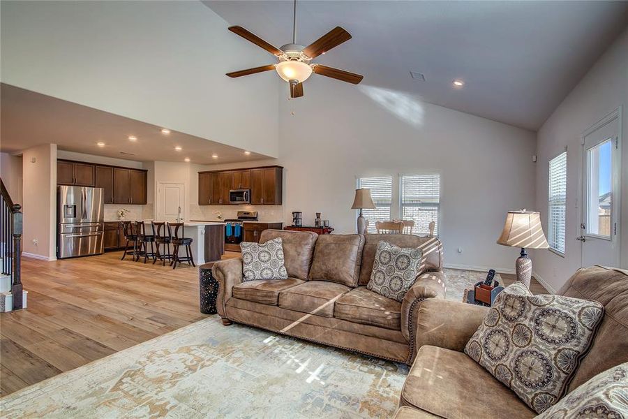 Living room featuring light wood-type flooring, high vaulted ceiling, a wealth of natural light, and ceiling fan