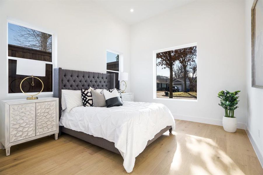 Bedroom with multiple windows, light hardwood / wood-style flooring, and high vaulted ceiling