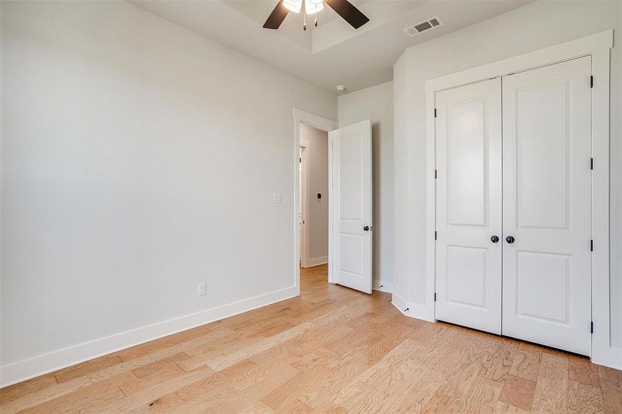 Unfurnished bedroom with a closet, light hardwood / wood-style floors, and ceiling fan