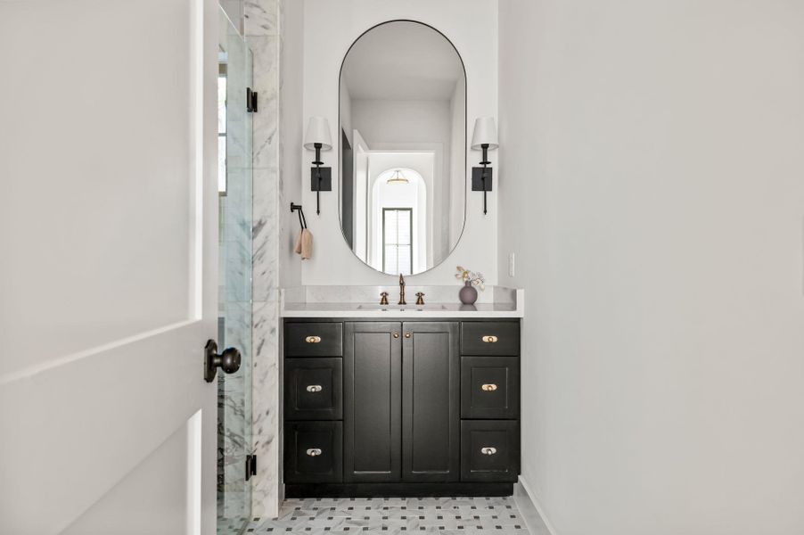 A well-appointed bathroom features a dark vanity with marble counters and a stylish oval mirror.