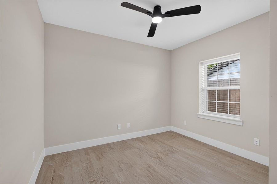 Bright and inviting room featuring neutral tones, elegant wood flooring, and a modern ceiling fan, providing a cozy and comfortable space.