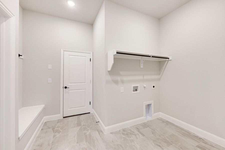 Laundry room with wall-mounted shelf, hanging rod, washer hookups, and marble tile floors Laundry room with wall-mounted shelf, hanging rod, washer hookups, and marble tile floors