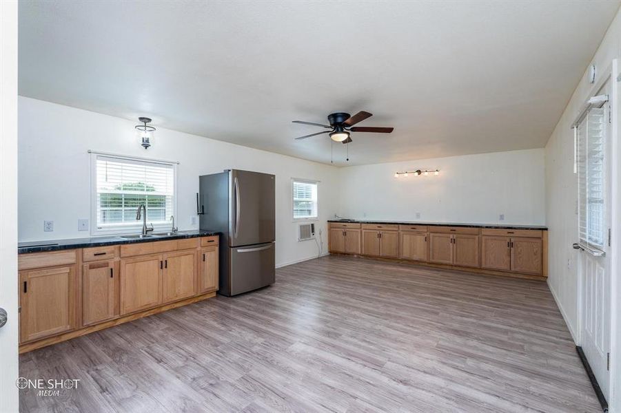Kitchen with stainless steel fridge, sink, light hardwood / wood-style flooring, and ceiling fan