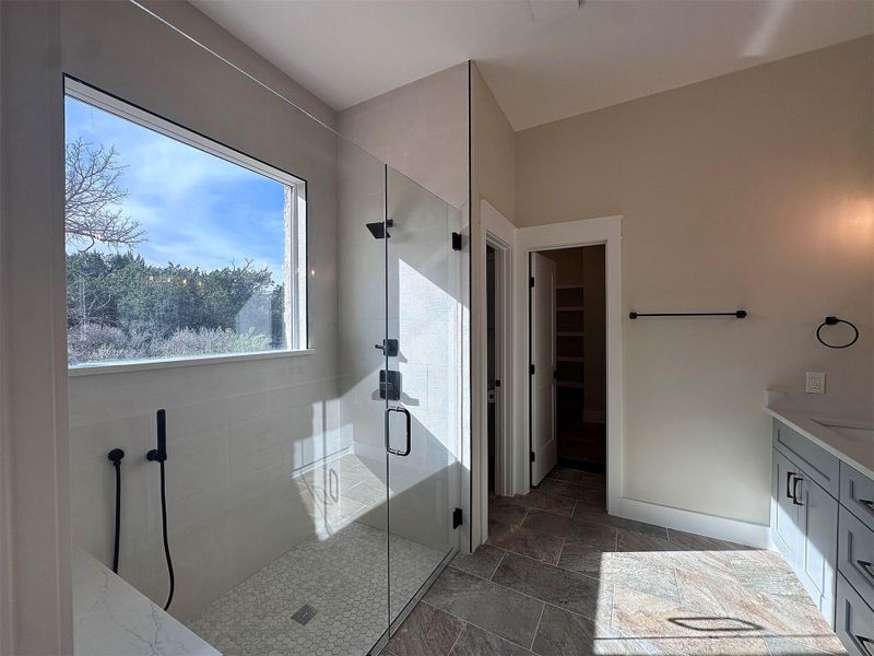 Full Master bath featuring vanity, oversized shower with seat bench, separate water closet,  a spacious clothing closet, and stone tile floors