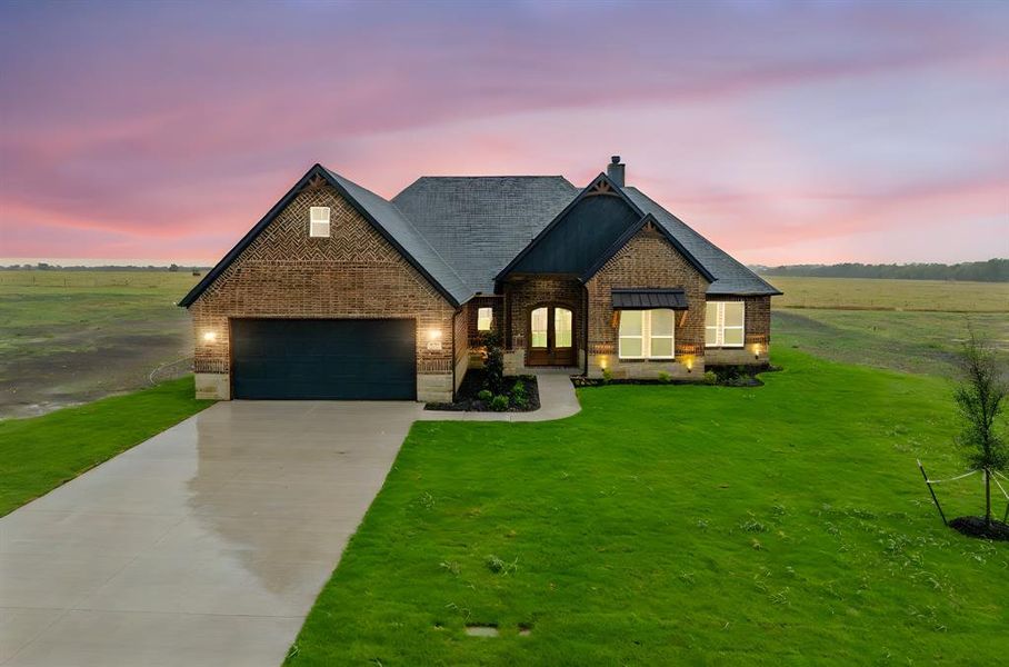 View of front of house featuring a garage and a lawn