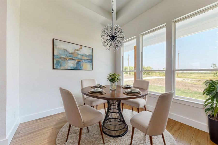 Dining area with light wood-type flooring and a tray ceiling