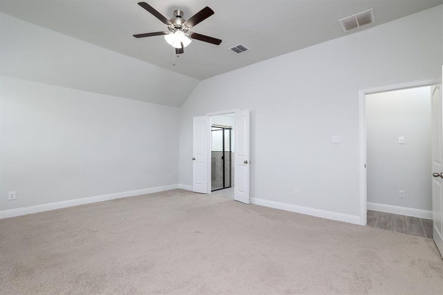 Unfurnished bedroom featuring light carpet, lofted ceiling, and ceiling fan
