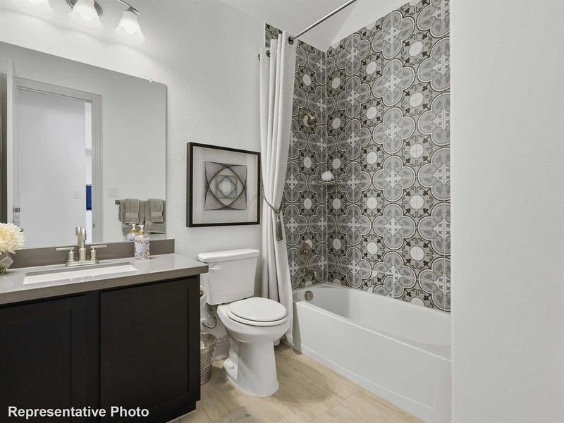 The bathroom features a vanity with a dark cabinet and light countertop, a toilet, and a bathtub with patterned wall tiling