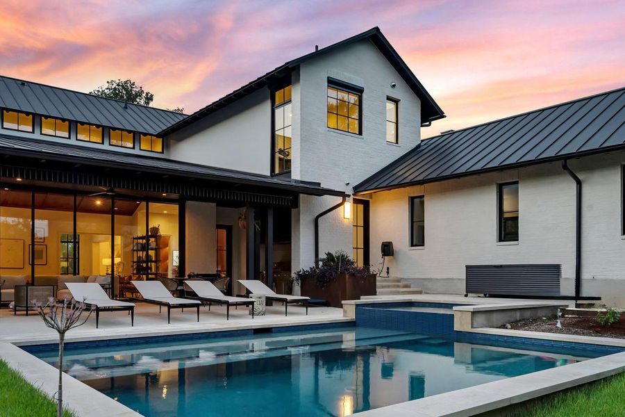 A tranquil backyard oasis features a glistening heated and chilled pool and covered patio, complementing the modern architecture.