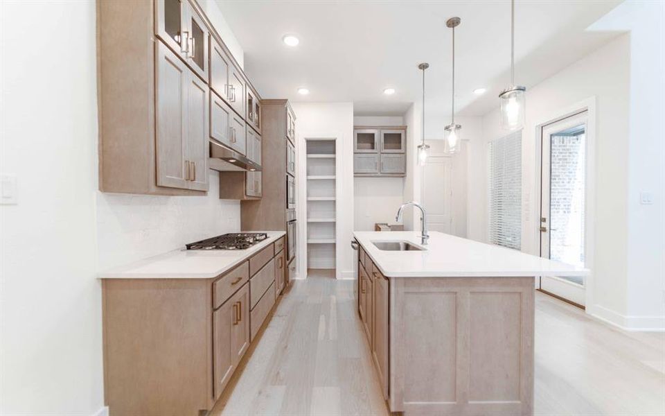 Kitchen featuring wood-finish cabinetry, light-toned countertops, and light wood-finish flooring
