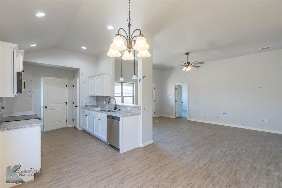 Kitchen with a chandelier, white cabinetry, tasteful backsplash, open floor plan, and light wood-type flooring
