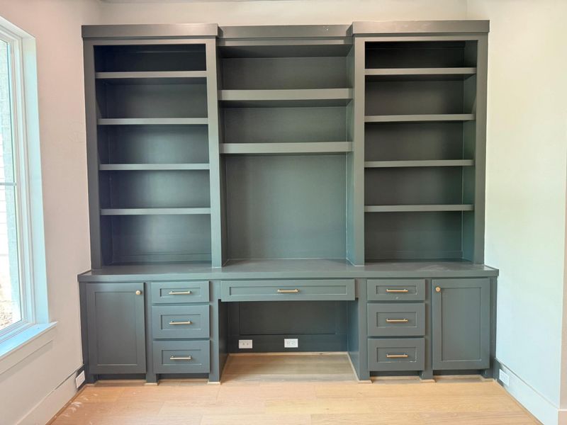 Unfurnished office featuring built in desk, healthy amount of natural light, and light wood-type flooring