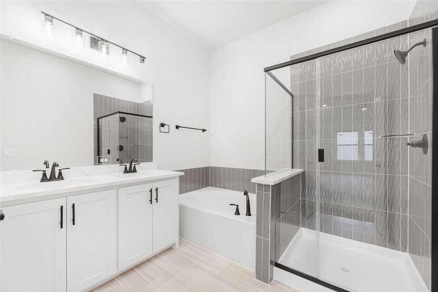 Master bathroom with double vanity, soaking tub, and glass walk-in shower with gray tile Master bathroom with double vanity, soaking tub, and glass walk-in shower with gray tile