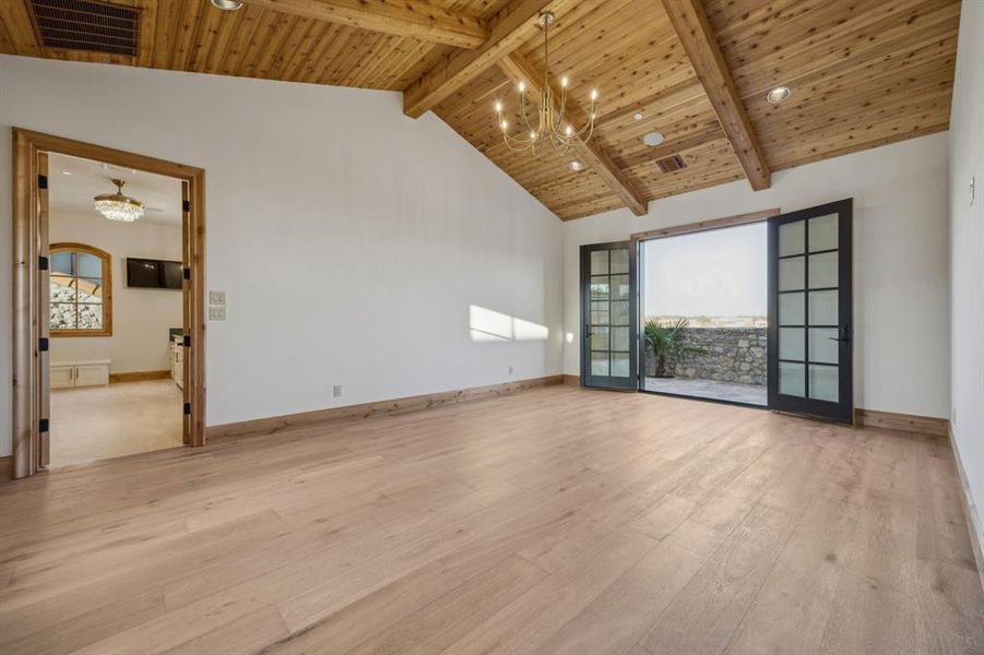 Spare room with a chandelier, light wood finished floors, high vaulted ceiling, and a wooden ceiling with exposed beams