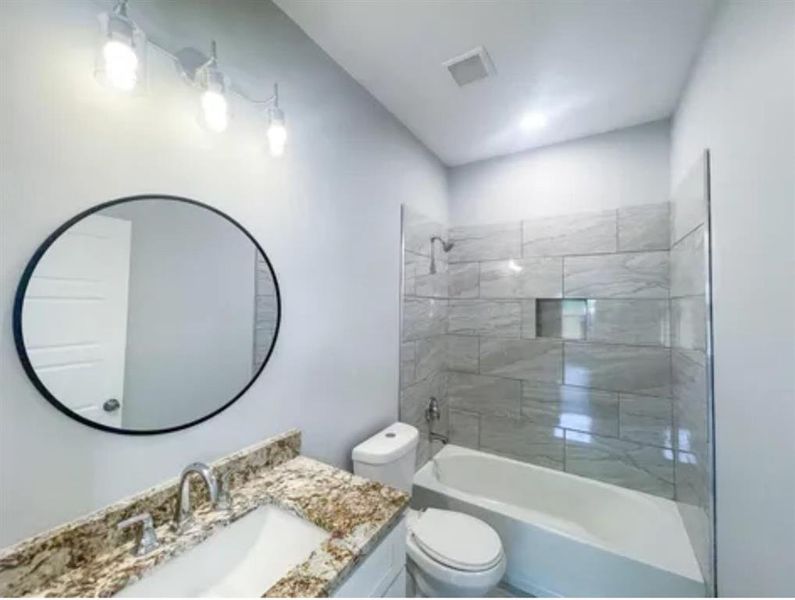 Full bathroom featuring vanity, toilet, and tiled shower / bath Full bathroom featuring vanity, toilet, and tiled shower / bath