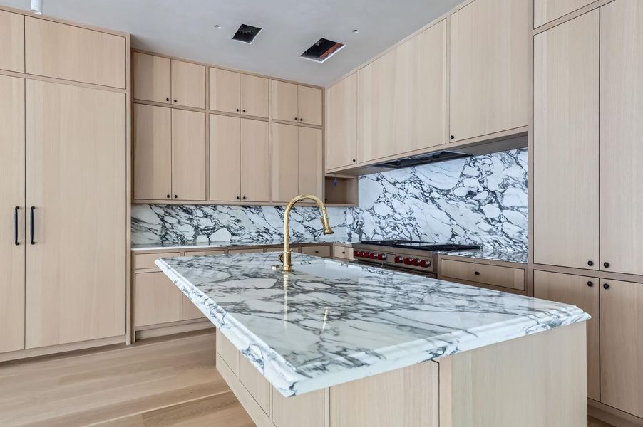 Marble countertops and a gold faucet create a refined and functional kitchen island.