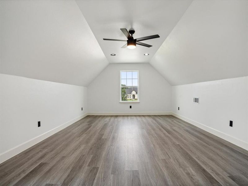 Additional living space featuring ceiling fan, hardwood / wood-style flooring, and vaulted ceiling