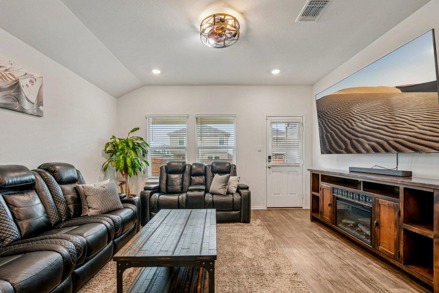 Living area with wood finished floors, vaulted ceiling, and recessed lighting